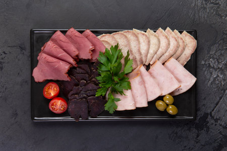 Assorted meat delicacies on a dark background. Selective focus.