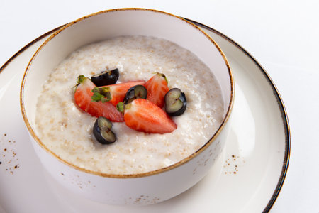Porridge with milk with berries in a plate on a white background. Selective focus.の写真素材
