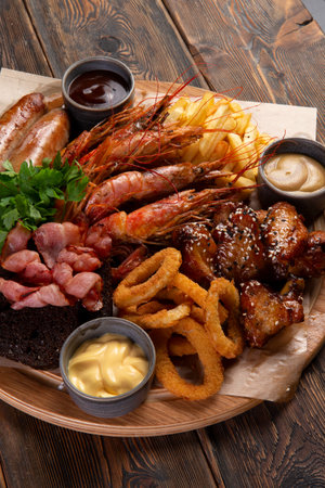 Assorted snacks for beer. Sausages, shrimp, fried chicken legs, onion rings on a wooden background. selective focus.の写真素材