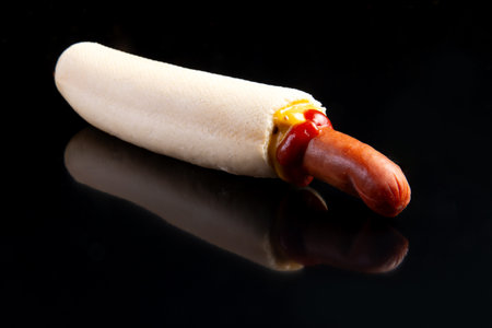 Hotdog with mustard and ketchup on a black background. Selective focus.の写真素材
