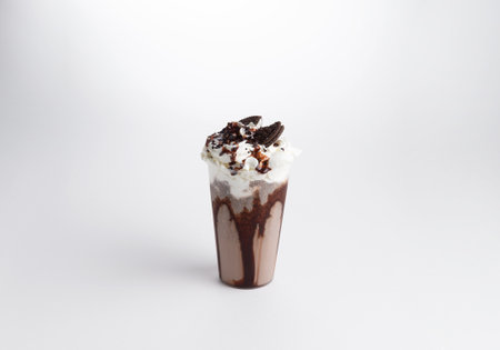 Milkshake with syrup, whipped cream and cookies in a glass. on a white background. Selective focus.