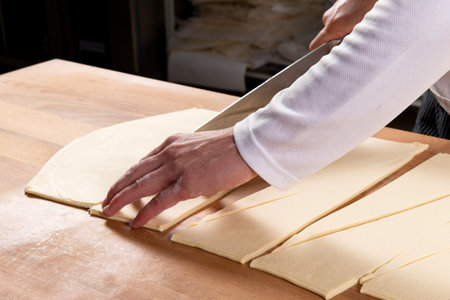 Pastry chef cutting puff pastry for croissants. Selective focus.の写真素材