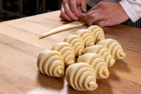 Pastry chef rolls dough into croissants. Selective focus.の写真素材