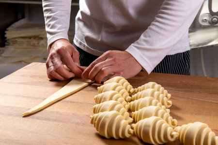 Pastry chef rolls dough into croissants. Selective focus.の写真素材