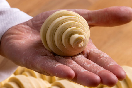 Hand holding a puff pastry croissant ready to be baked. Selective focus.