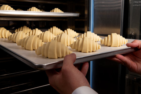 Pastry chef places croissants in the oven. Selective focus.