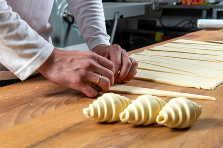 Pastry chef rolls dough into croissants. Selective focus.の写真素材
