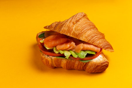 Croissant with salmon and avocado on a yellow background. Selective focus.の写真素材