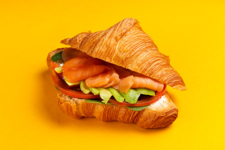 Croissant with salmon and avocado on a yellow background. Selective focus.の写真素材