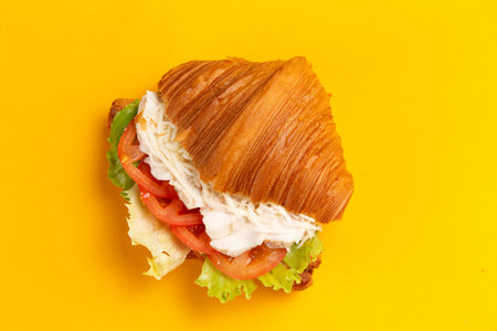 Croissant with chicken and tomatoes on a yellow background. Selective focus.の写真素材