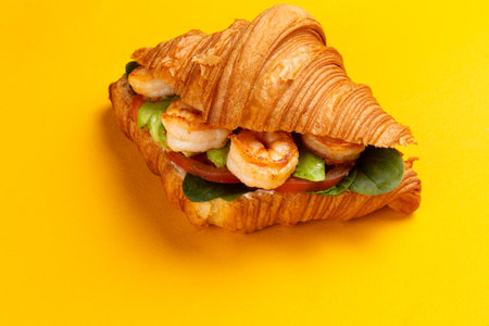 Croissant with shrimp and avocado on a yellow background. Selective focus.の写真素材