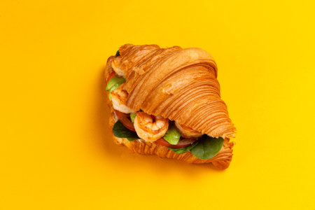 Croissant with shrimp and avocado on a yellow background. Selective focus.の写真素材