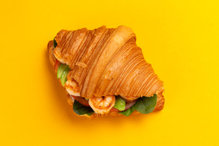 Croissant with shrimp and avocado on a yellow background. Selective focus.の写真素材
