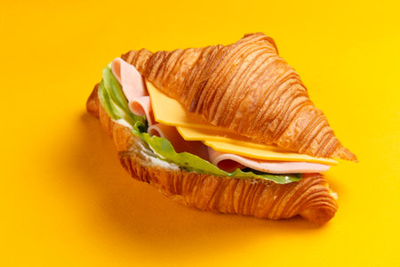 Croissant with cheese and ham on a yellow background. Selective focus.