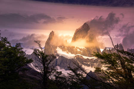 Rocky snowy mountain peaks with the sun rising behind and red clouds. Fitz Roy in Argentinaの写真素材