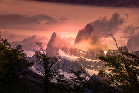 Rocky snowy mountain peaks with the sun rising behind and red clouds. Fitz Roy in Argentinaの写真素材