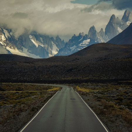 Asphalted road with the peaks of a rocky and snowy mountain on the horizon. Fitz Roy mountain in Argentinaの写真素材