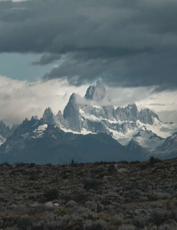 Asphalted road with the peaks of a rocky and snowy mountain on the horizon. Fitz Roy mountain in Argentina vertical Photographの写真素材