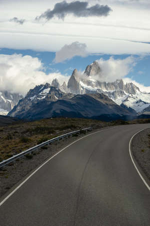 Asphalted road with the peaks of a rocky and snowy mountain on the horizon. Fitz Roy mountain in Argentina vertical Photographの写真素材