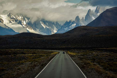 Asphalted road with the peaks of a rocky and snowy mountain on the horizon. Fitz Roy mountain in Argentina vertical Photographの写真素材