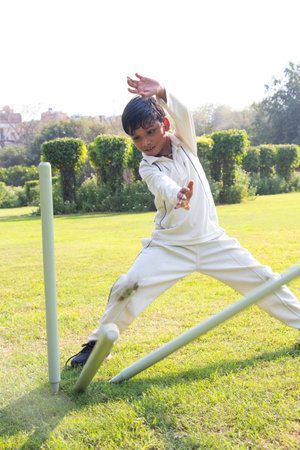 a boy fielding on the ground during cricket gameの写真素材