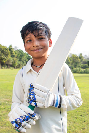 Boy in cricket uniform holding a cricket batの写真素材