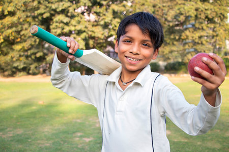 Portrait of a boy holding a cricket bat and a cricket ballの写真素材