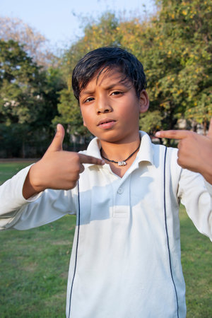 A boy in cricket uniform and pointing