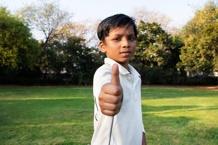 A boy in cricket uniform and pointing