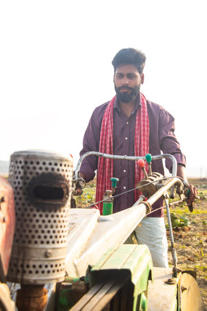 Indian Man using the power tiller to plough the fieldsの写真素材