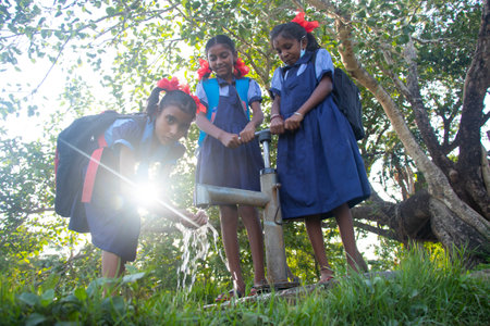 Indian Rural School Girls drinking water from Tubewell at villageの写真素材