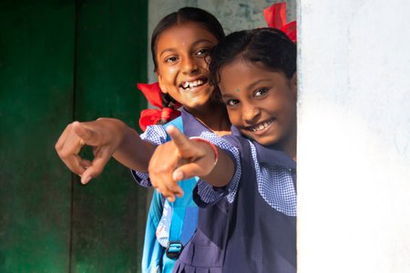 portrait of a rural school girls  pointing at schoolの写真素材