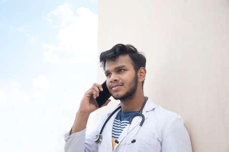 Male doctor talking on a smart phone in lab coatの写真素材