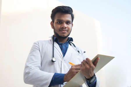 A health worker in Lab Coat Writing a notepad and penの写真素材