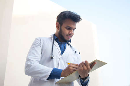 A health worker in Lab Coat Writing a notepad and penの写真素材