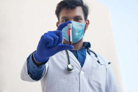 A doctor wearing face mask analyzing a blood sampleの写真素材