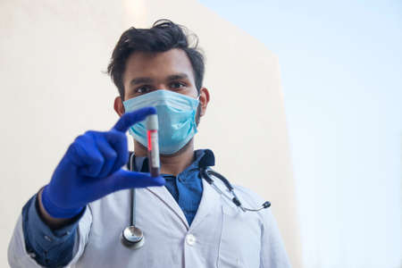 A doctor wearing face mask analyzing a blood sampleの写真素材
