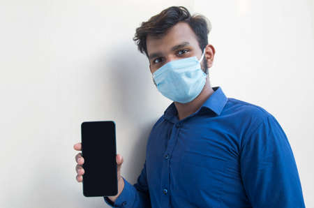 A young man with face mask and Showing Mobile phoneの写真素材