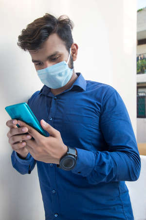 A young man with face mask and a Mobile phoneの写真素材