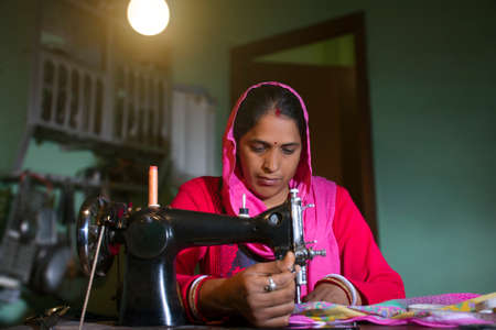 PORTRAIT OF A RURAL WOMAN SEWING CLOTHESの写真素材
