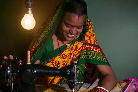 PORTRAIT OF A RURAL WOMAN SEWING CLOTHES AND SMILINGの写真素材