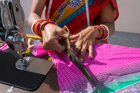 CLOSE_UP PORTRAIT OF A RURAL WOMAN cutting dress with sewing machineの写真素材