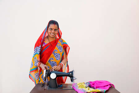 confident woman standing with sewing machine in rural Indiaの写真素材