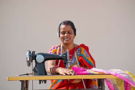 PORTRAIT OF A RURAL WOMAN listening music AND SEWING CLOTHESの写真素材