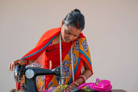 Indian woman stitching cloths by machine  in rural Indiaの写真素材