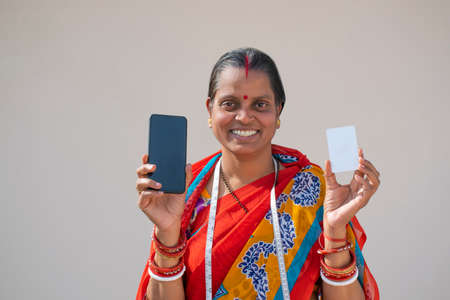 PORTRAIT OF A RURAL WOMAN HOLDING MOBILE PHONE AND CARDの写真素材