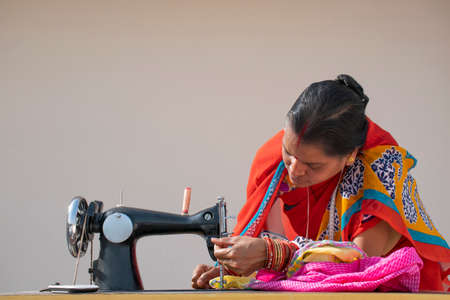 Indian woman stitching cloths by machine  in rural Indiaの写真素材