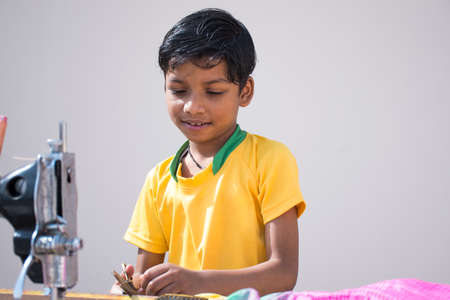 Indian boy sitting with sewing machine in rural Indiaの写真素材