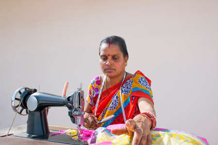 PORTRAIT OF A RURAL WOMAN cutting dress with sewing machineの写真素材
