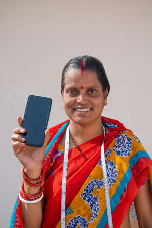 PORTRAIT OF A RURAL WOMAN HOLDING MOBILE PHONEの写真素材